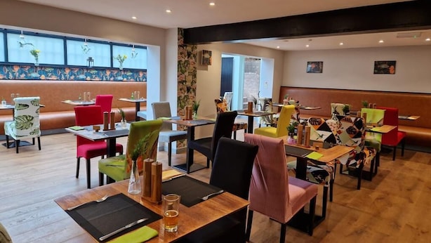 A restaurant with booths and tables, wooden flooring, and a large window with a view. - The Noel at Whitwell (Oakham)