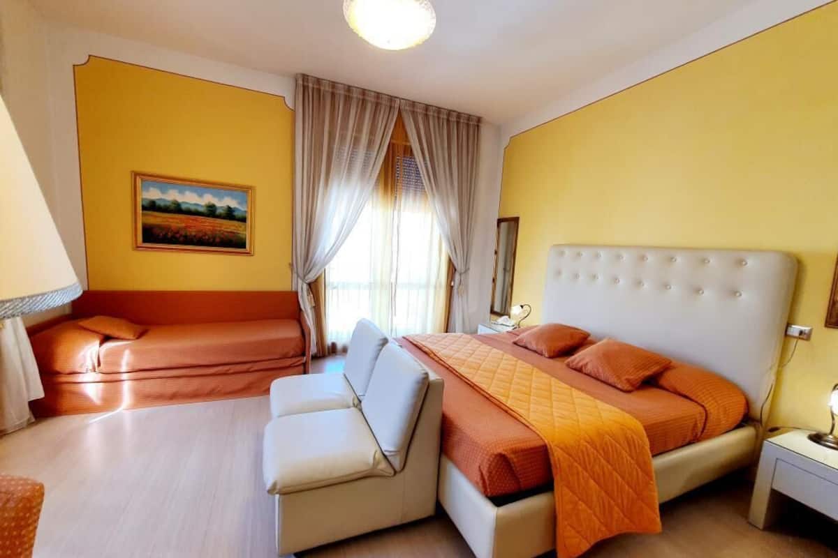A bedroom with a bed, a sofa, a desk, and a painting on the wall.
