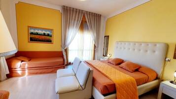 Ein Schlafzimmer mit einem Bett, einer Couch, einem Schreibtisch und einem Bild an der Wand.