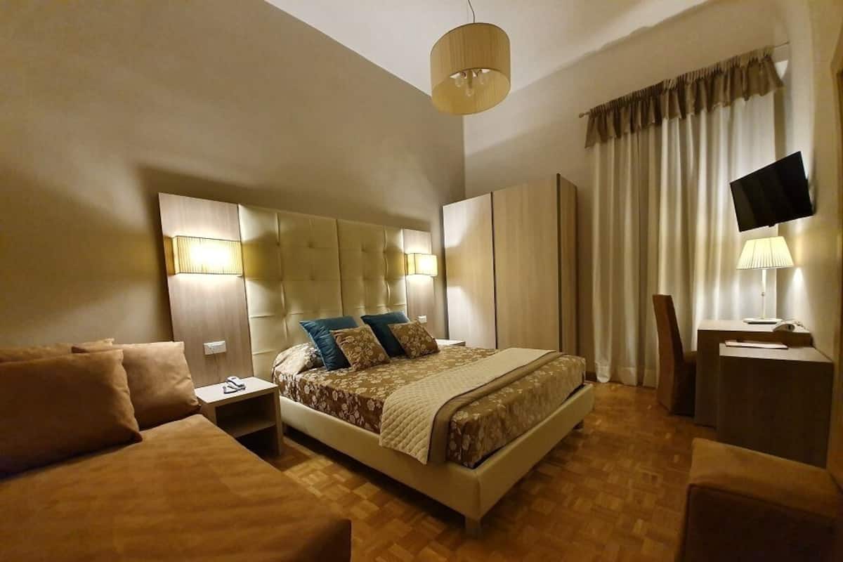 A hotel room with a large bed, bedside tables, a flat-screen TV, and a ceiling light.