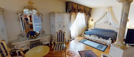 A luxurious bedroom with ornate furniture, a large bed with a canopy, a chandelier, and a mirror.