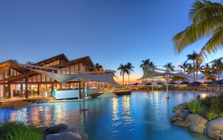 A resort with a swimming pool, lounge area, and a building with a wooden facade.