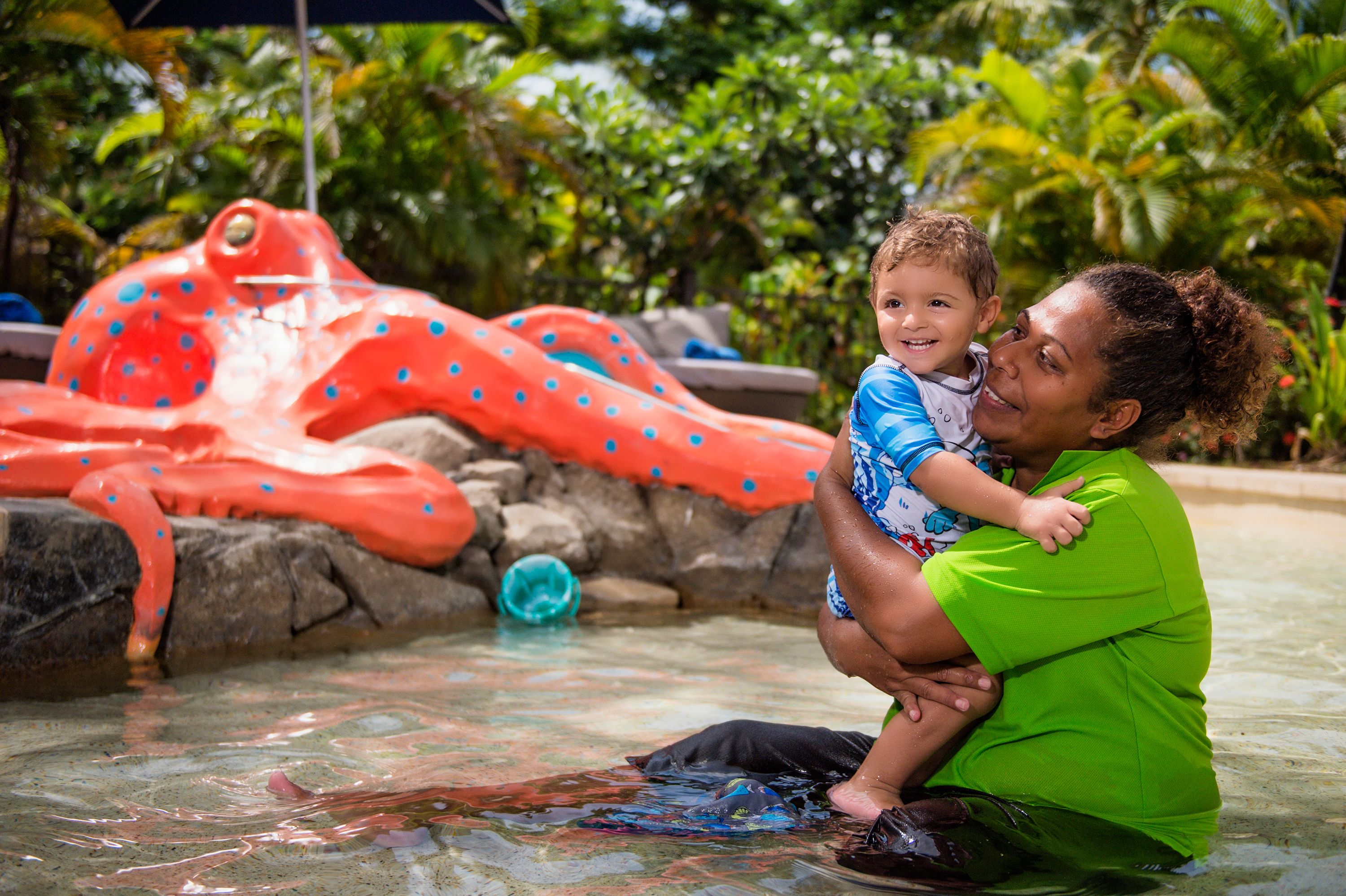 A person in a pool with a large inflatable octopus decoration.