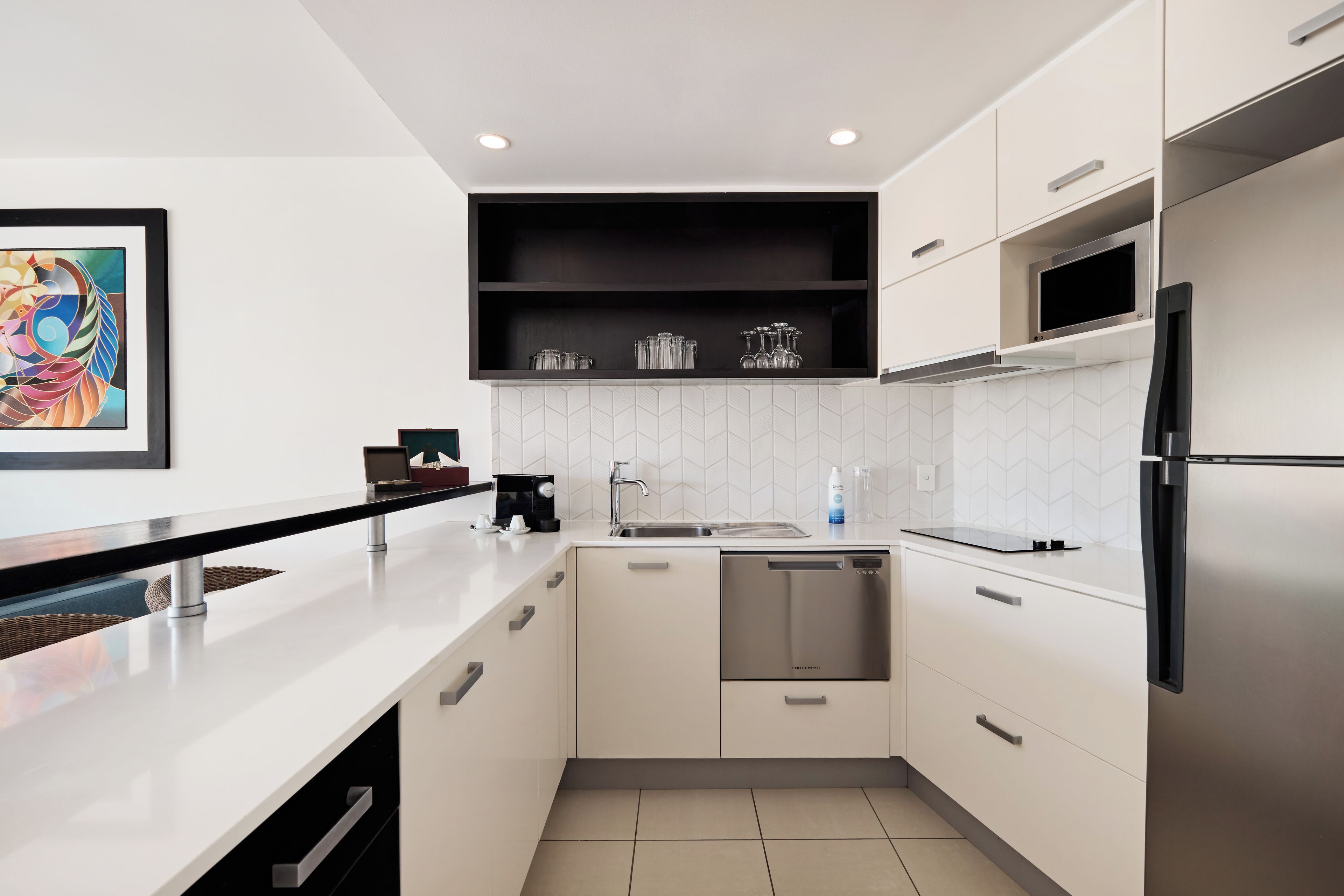 Une cuisine moderne avec des meubles blancs, un réfrigérateur en acier inoxydable et un micro-ondes noir.