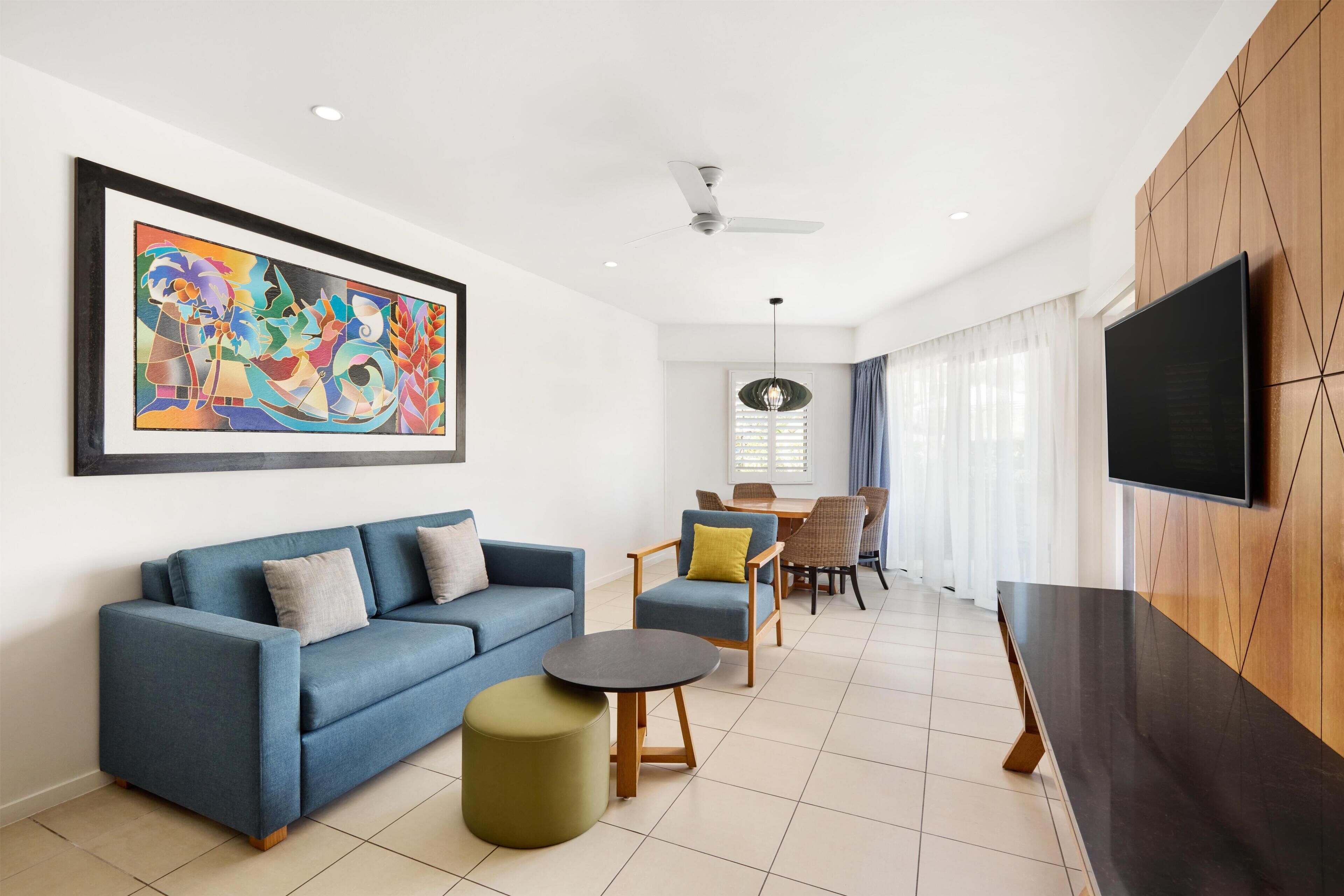 A modern living room with a sofa, ottoman, and dining area with chairs and a table.