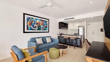 A modern living room with a sofa, a coffee table, a dining table, and a kitchen in the background.