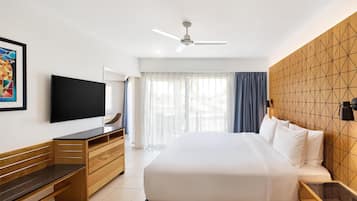 Habitación de hotel con cama, televisor, escritorio y ventilador de techo.