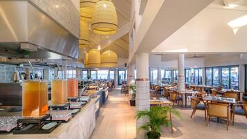 Un restaurant spacieux avec de hauts plafonds, de grandes fenêtres et un espace buffet.