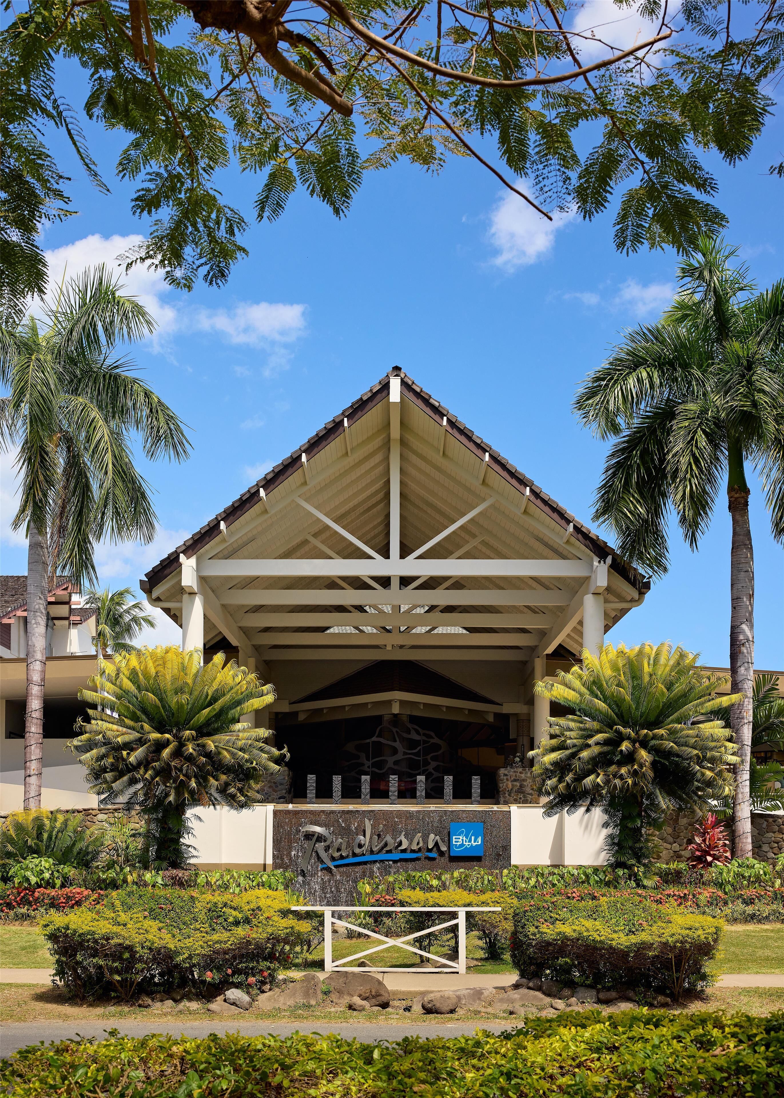 A building with a covered entrance, palm trees, and a sign that reads 'Radisson.'