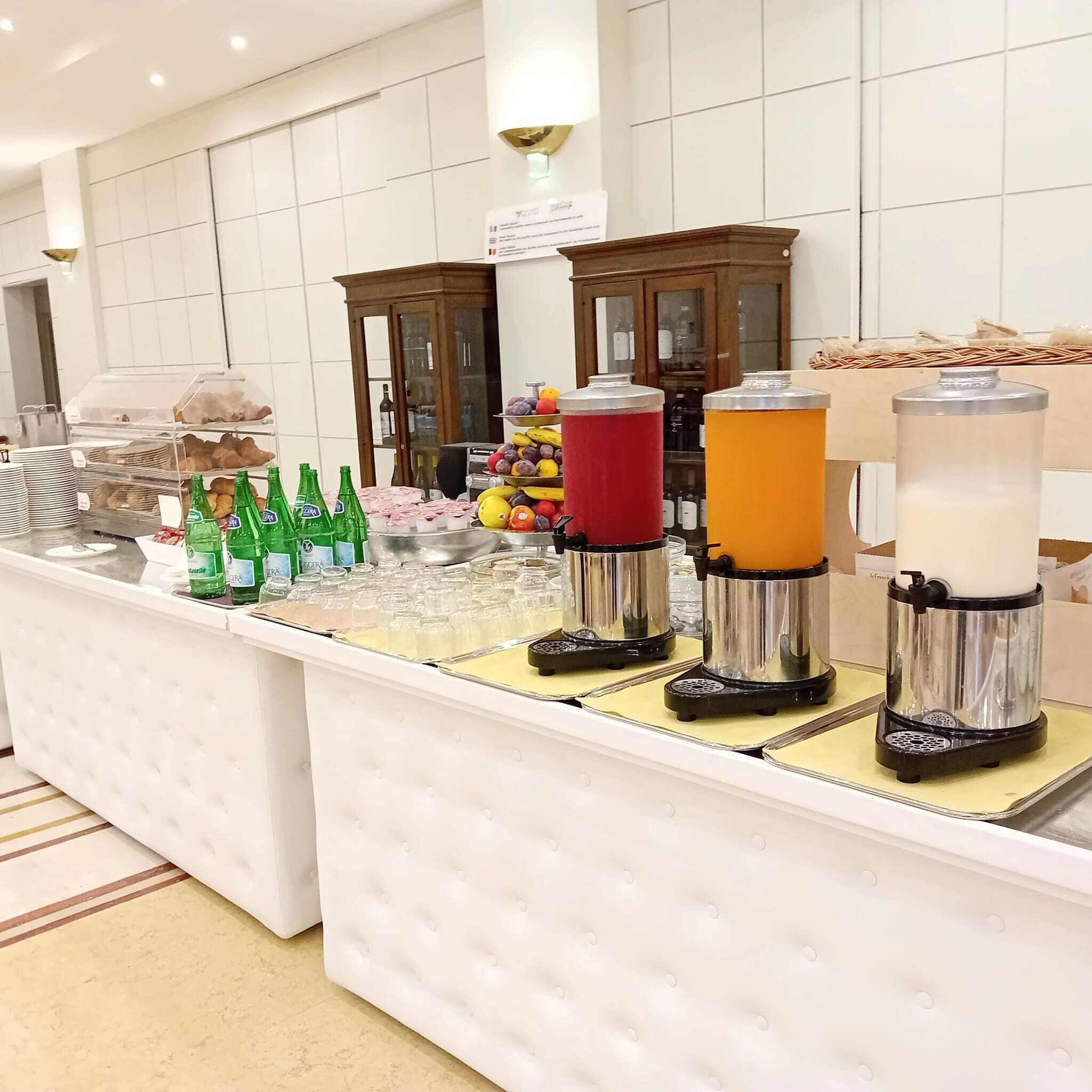 Un'area buffet con diversi cibi, bevande e una macchina per il caffè.