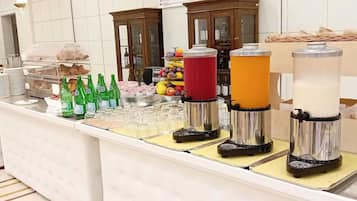 Zona de bufé con diferentes alimentos, bebidas y una máquina de café.