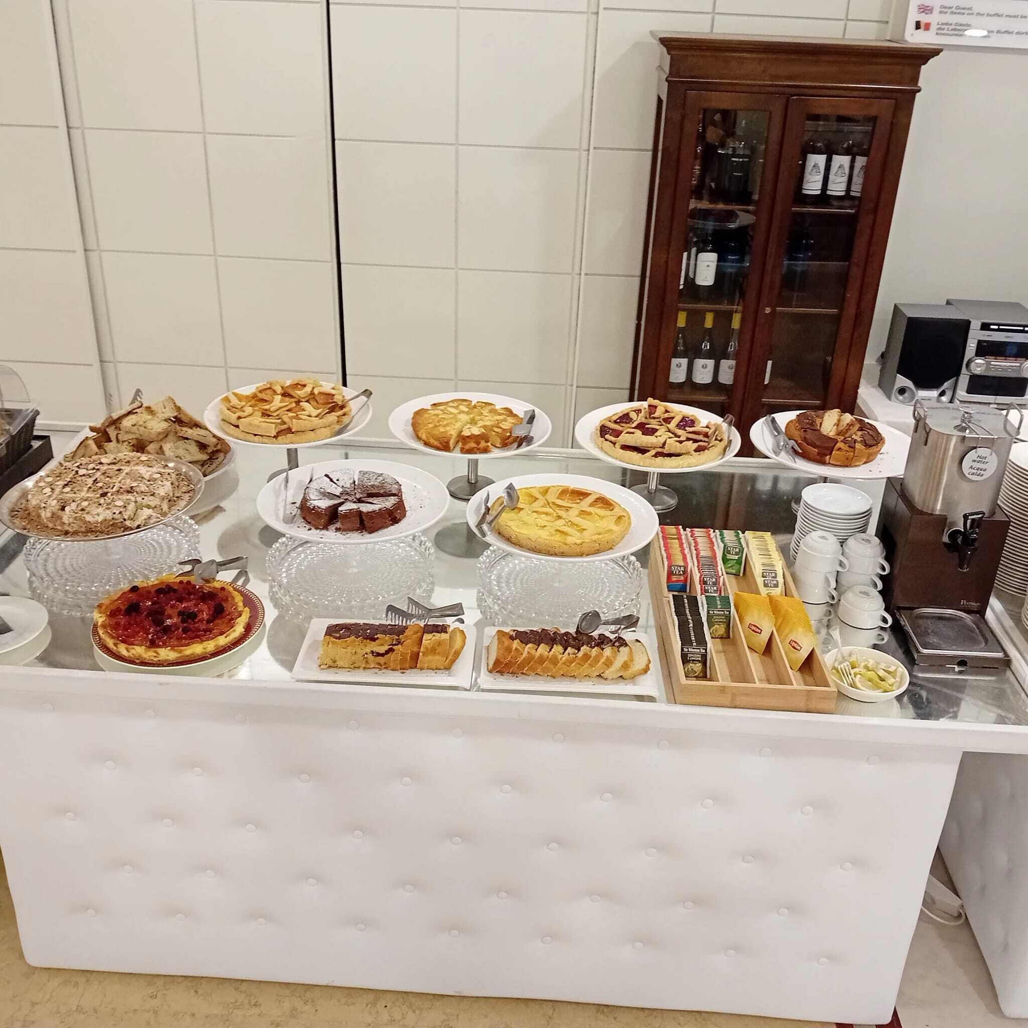 Une table de buffet proposant divers desserts, avec une sélection de vins en arrière-plan.