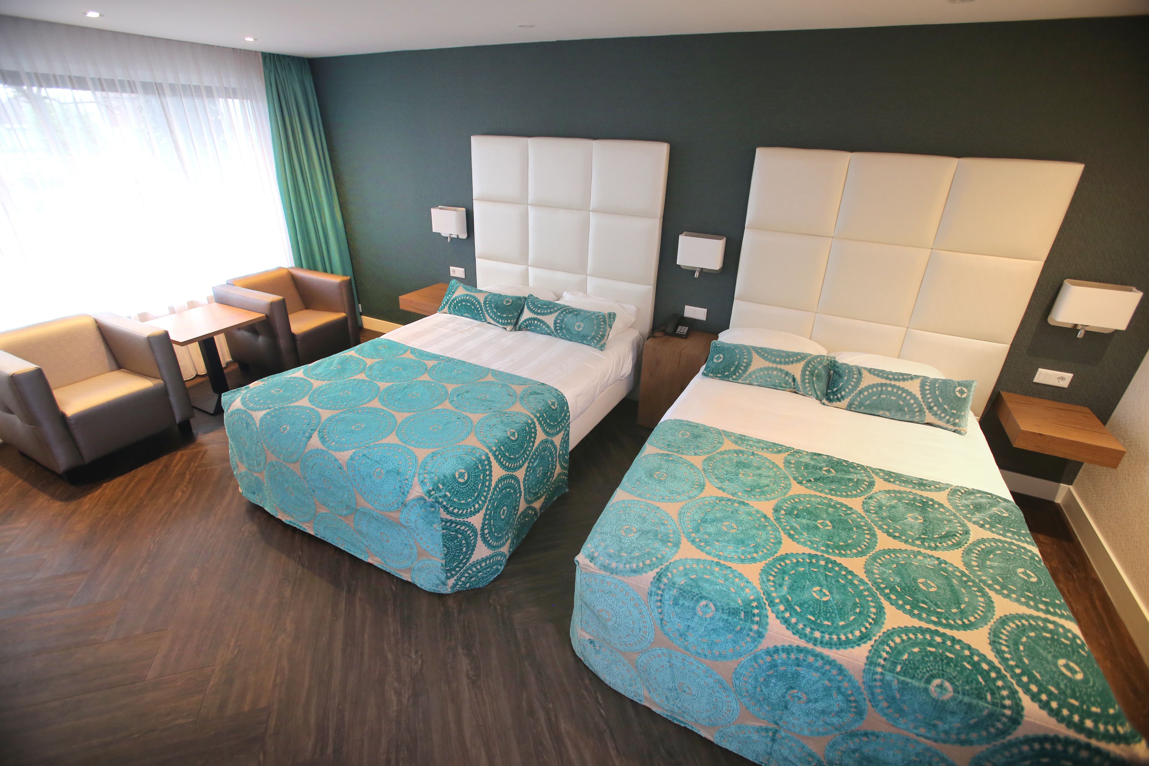 A hotel room with two beds, a small table, and a seating area.