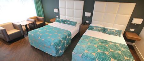 A hotel room with two beds, a small table, and a seating area.