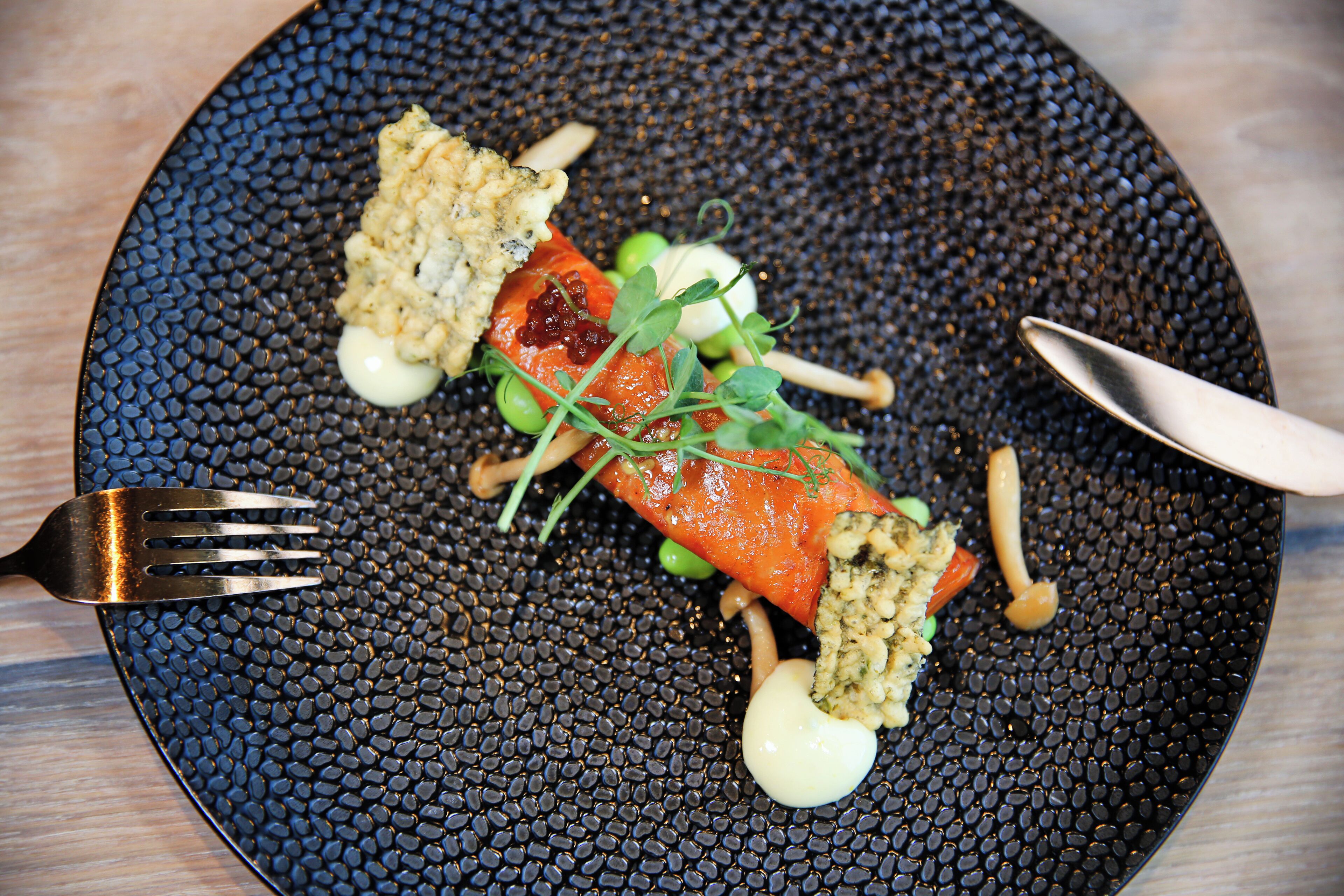Een bord met zalm, groenten en een klein beetje saus.