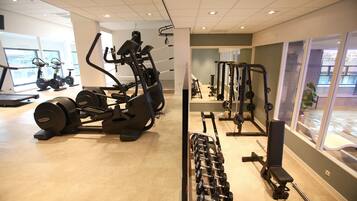A gym with various exercise equipment including treadmills, stationary bikes, and weight machines.