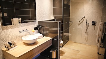 A modern bathroom with a large sink, a glass shower enclosure, and a mirror.