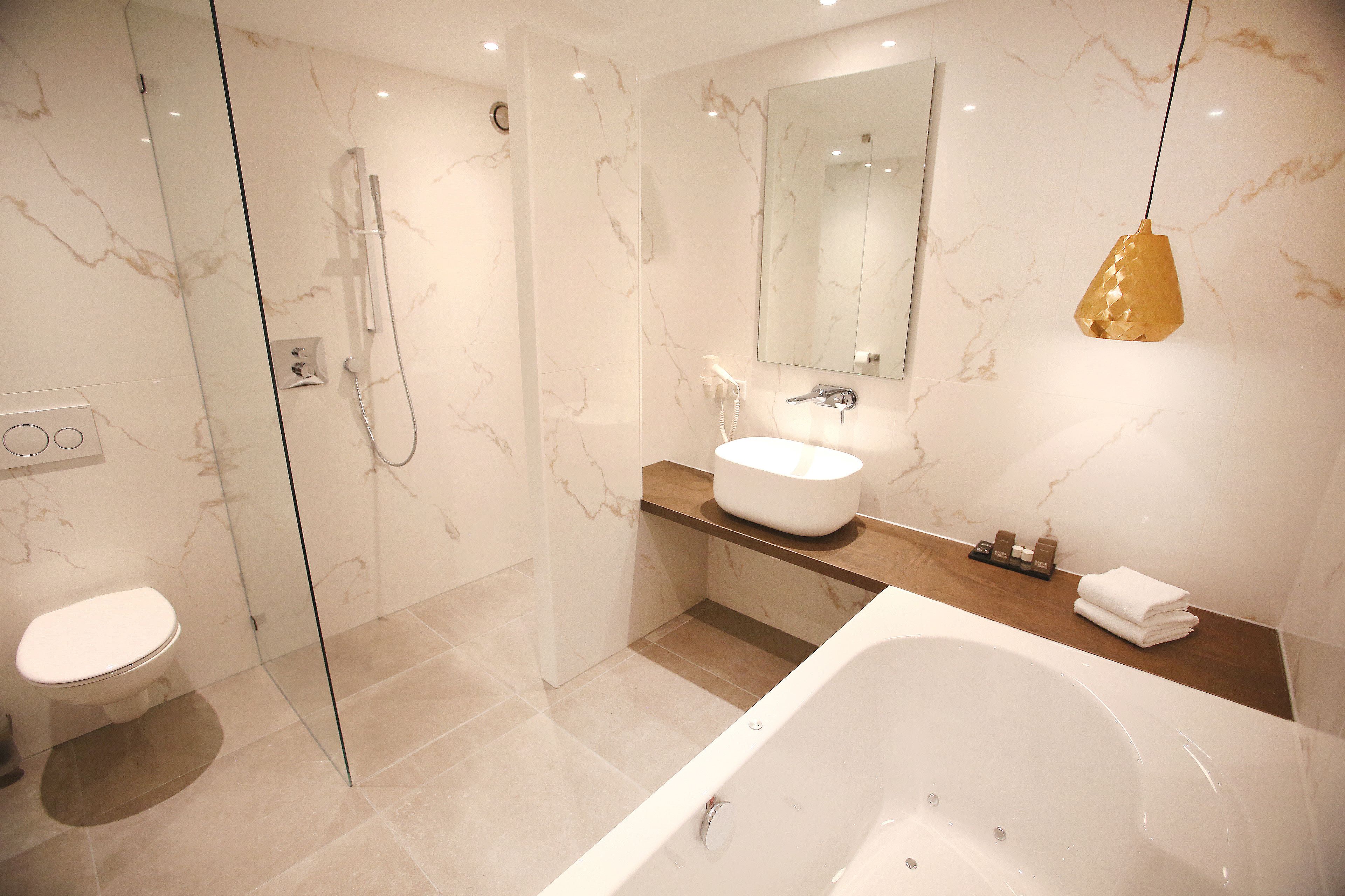 A modern bathroom with a glass-enclosed shower, a white bathtub, and a vanity with a sink and mirror.