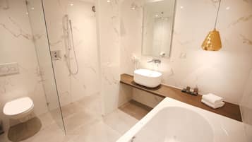 A modern bathroom with a glass-enclosed shower, a white bathtub, and a vanity with a sink and mirror.