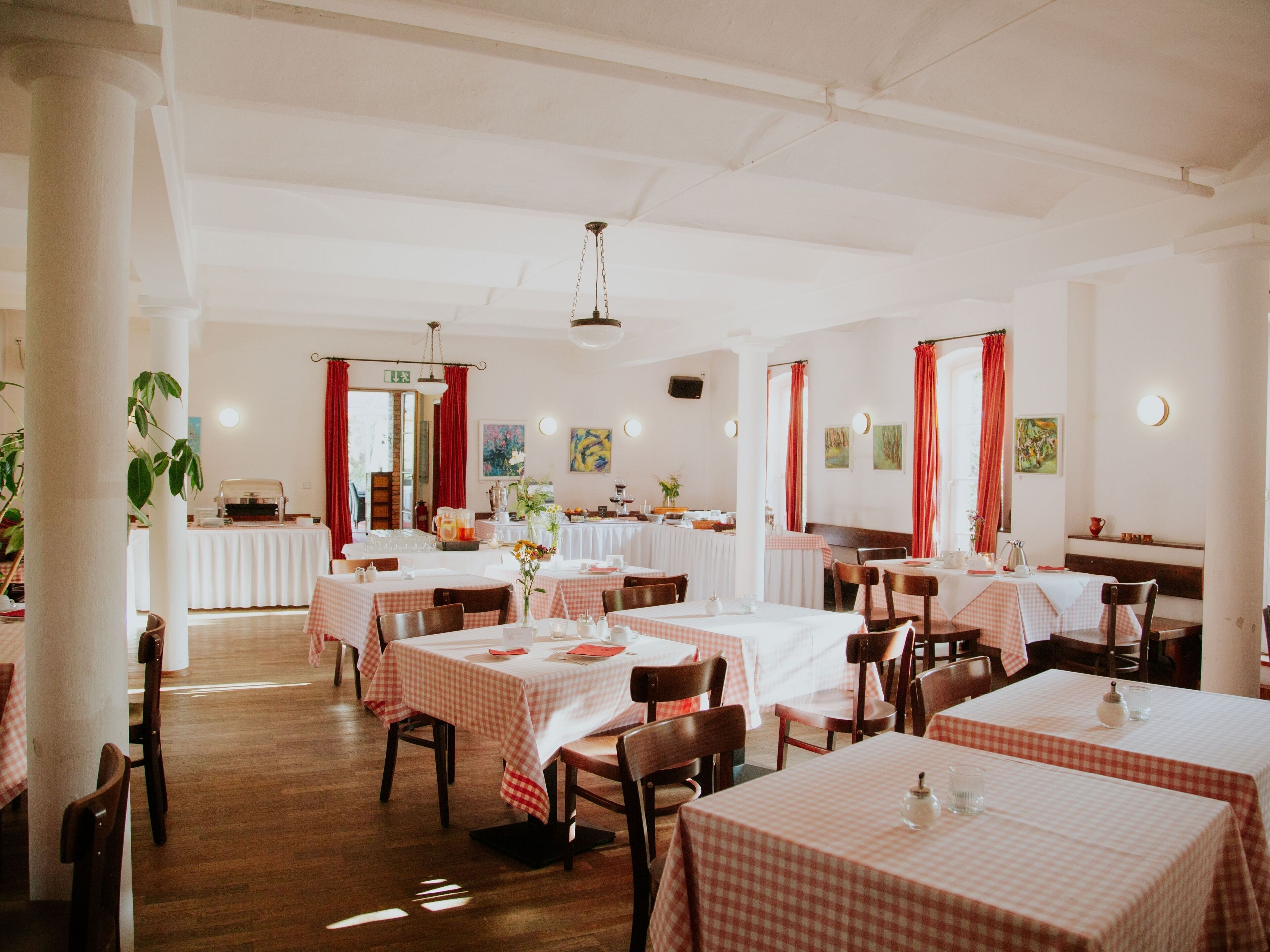 A restaurant with checkered tablecloths, wooden chairs, and a wooden floor.
