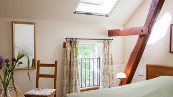 Un dormitorio con tragaluz, una cama, una silla, un escritorio y un ventanal con cortinas.