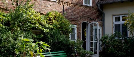 A brick house with a green bench in the garden.