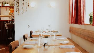 Comedor con una larga mesa de madera dispuesta para una comida, rodeado de sillas.