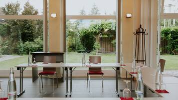 A dining area with a table set for six, large windows, and a view of the garden.