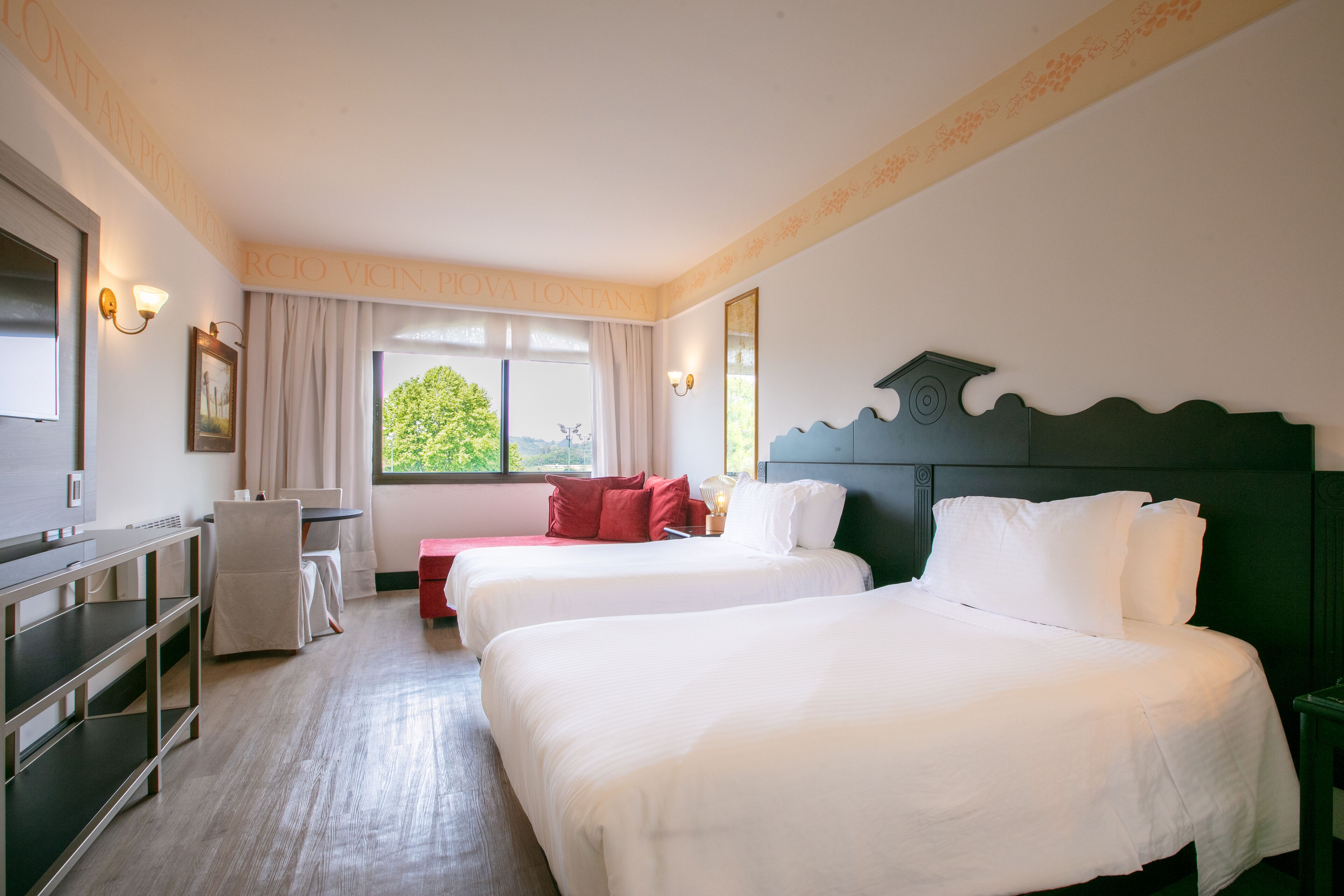 Una habitación de hotel con dos camas, un escritorio y una ventana con cortinas.