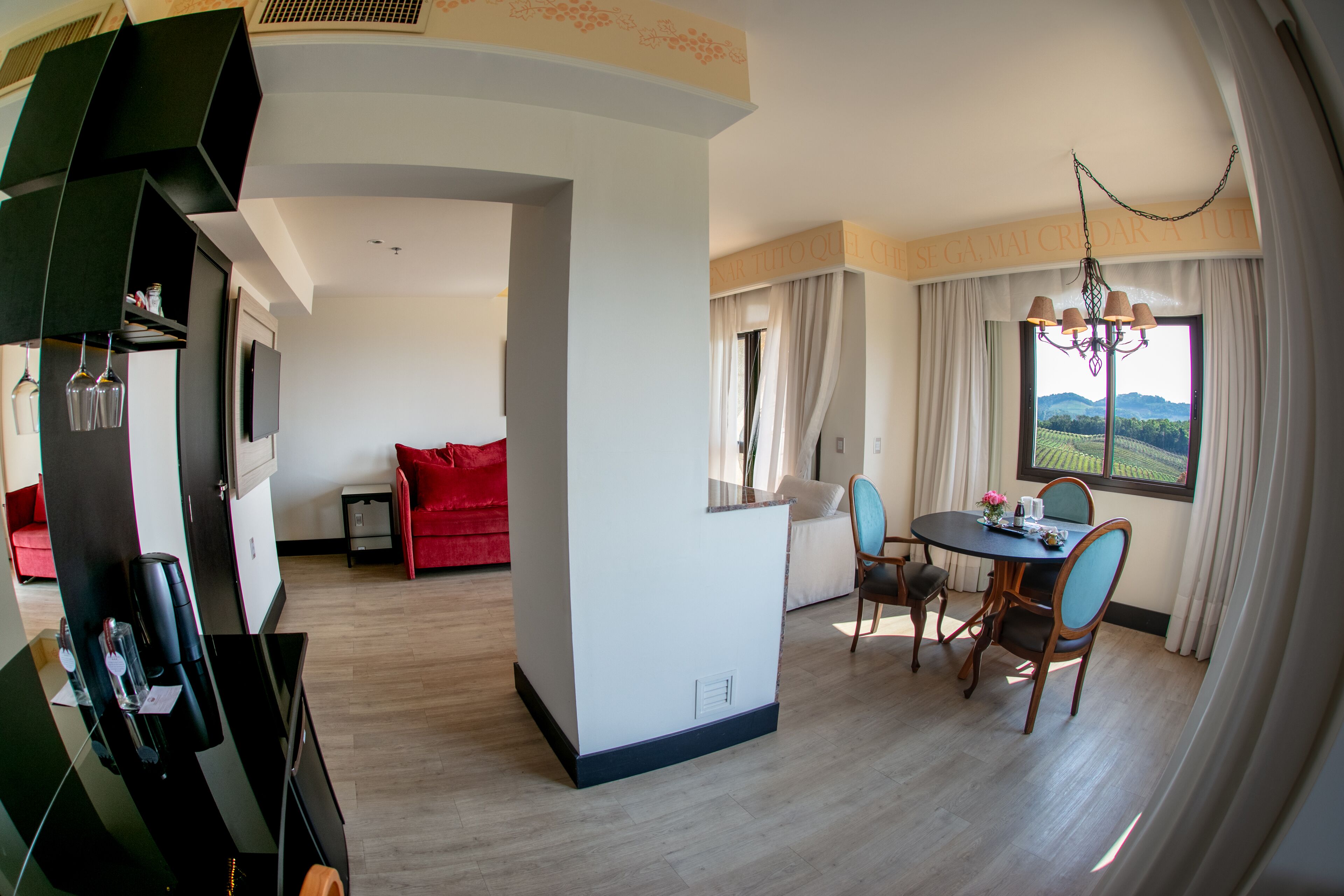 Una habitación de hotel moderna con comedor, un sofá rojo y vistas al campo.