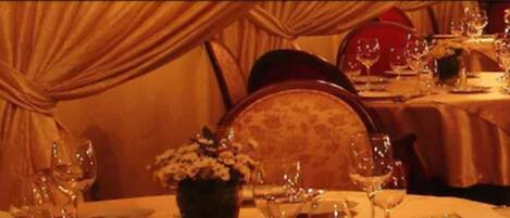 A dining area with tables set for a meal, featuring chairs and a vase with flowers.