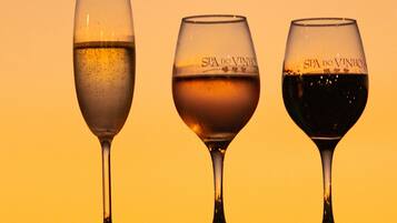 Tre bicchieri da vino su una ringhiera sullo sfondo di un tramonto.