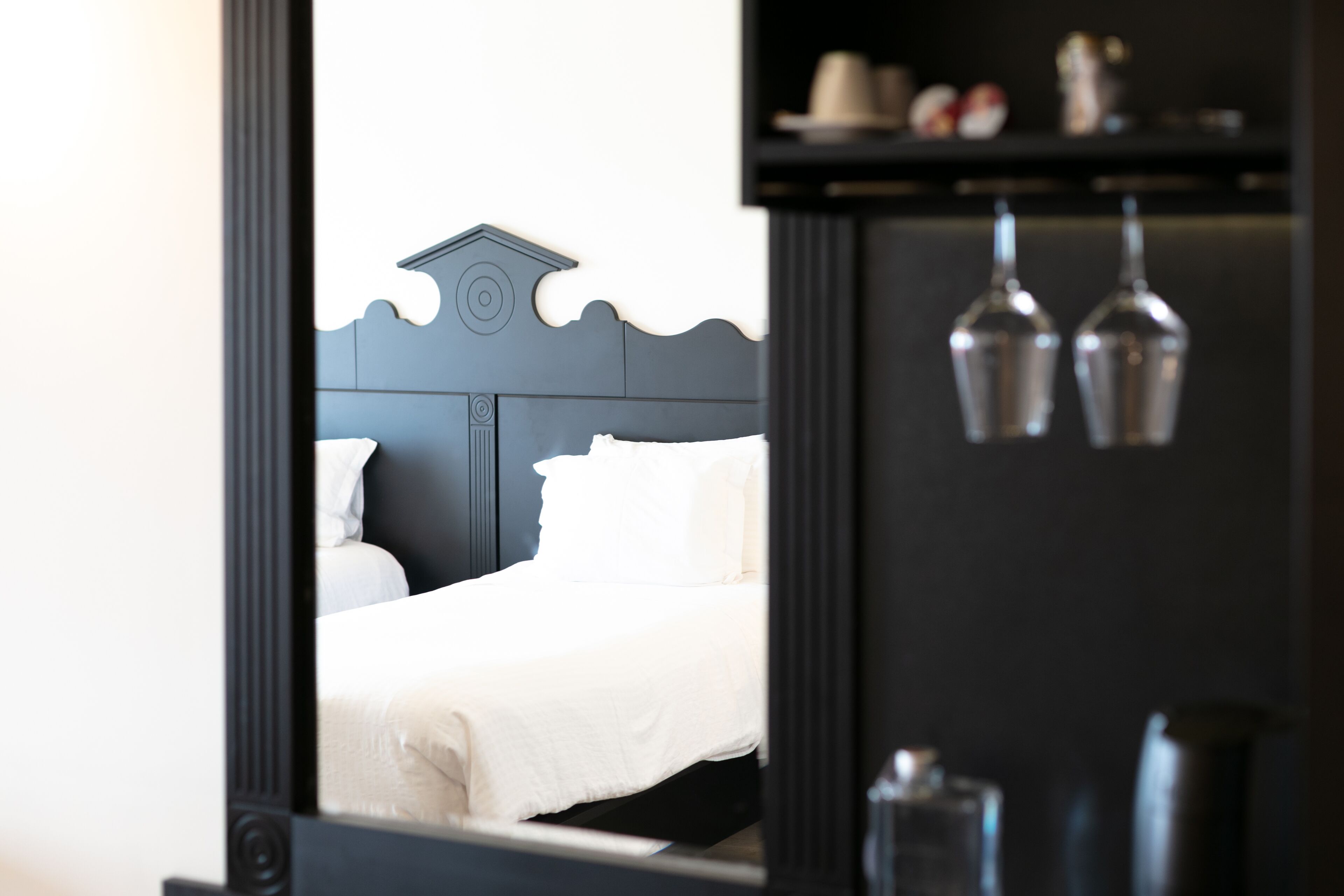 Un dormitorio con una cama, una mesita de noche y un espejo que refleja la habitación.