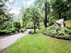 A park with a pathway, benches, and a stone sculpture.