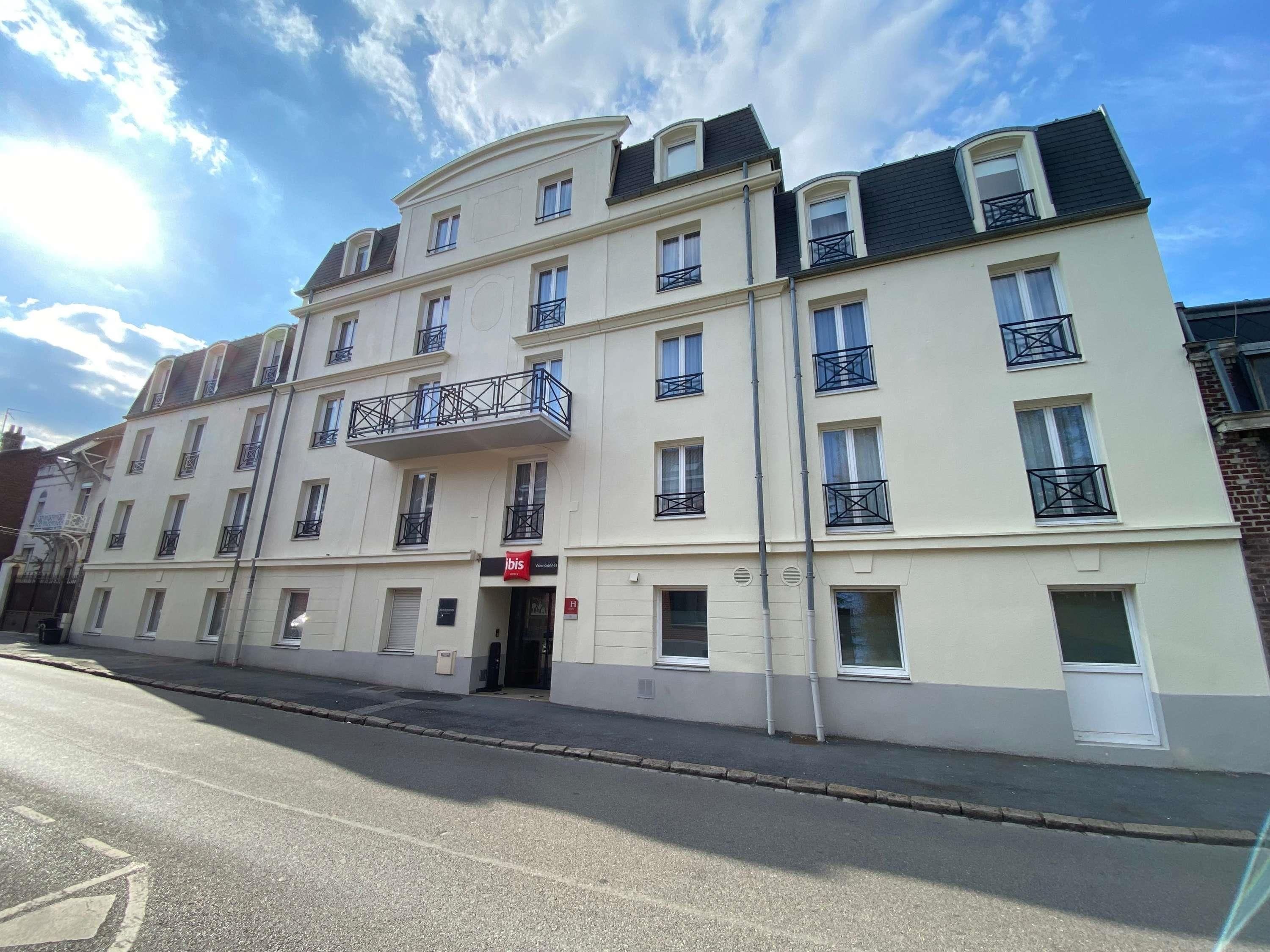 Un hôtel à plusieurs étages, doté de balcons, d’une entrée imposante et offrant une vue sur un ciel dégagé.