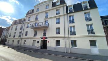 Un hôtel à plusieurs étages, doté de balcons, d’une entrée imposante et offrant une vue sur un ciel dégagé.