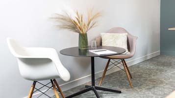 Una habitación moderna con una mesa redonda, dos sillas, un florero con plantas secas y una alfombra estampada.