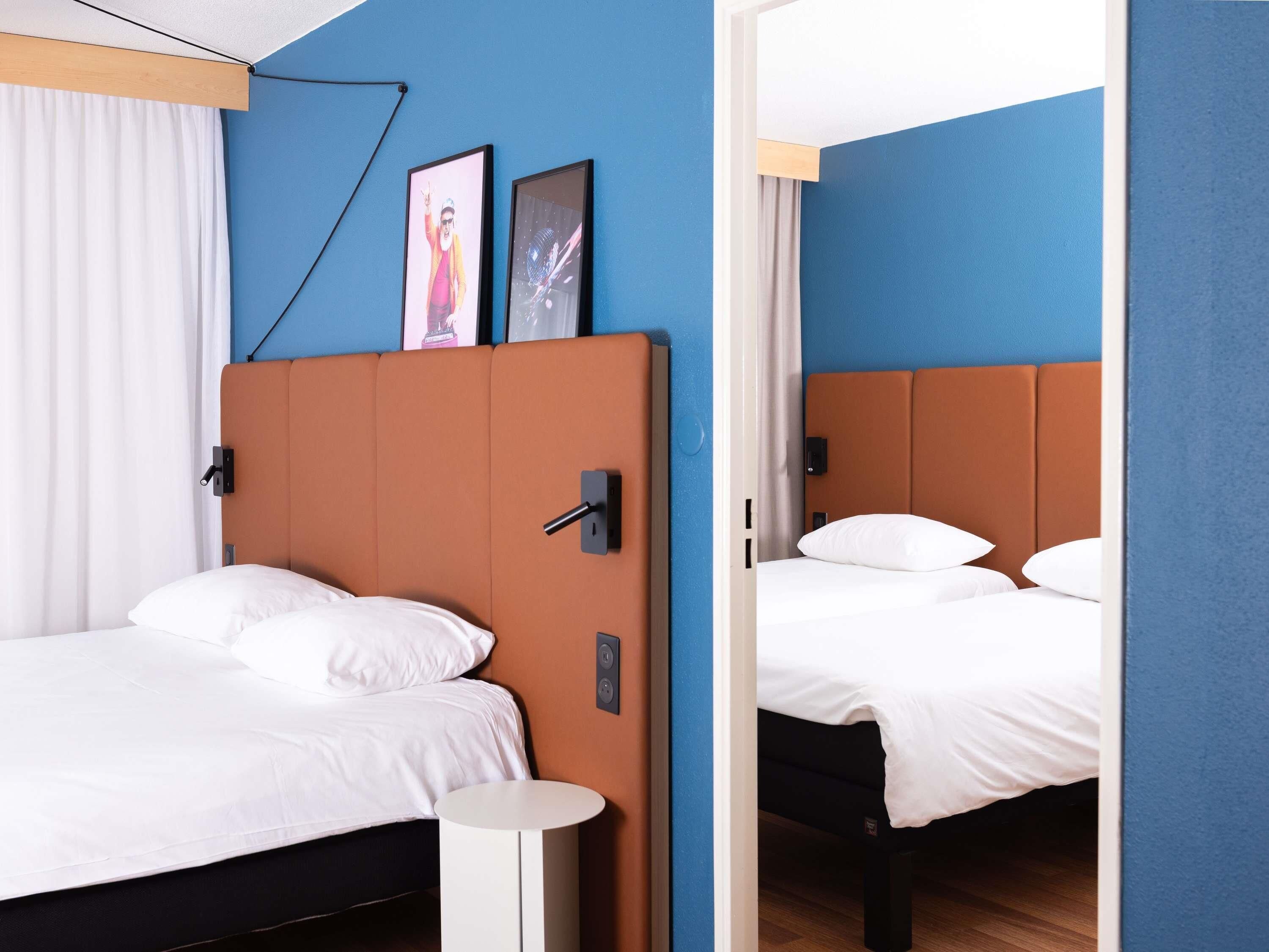 Una habitación de hotel moderna con una cama individual, una mesita de noche redonda y un cabecero con panel de control.