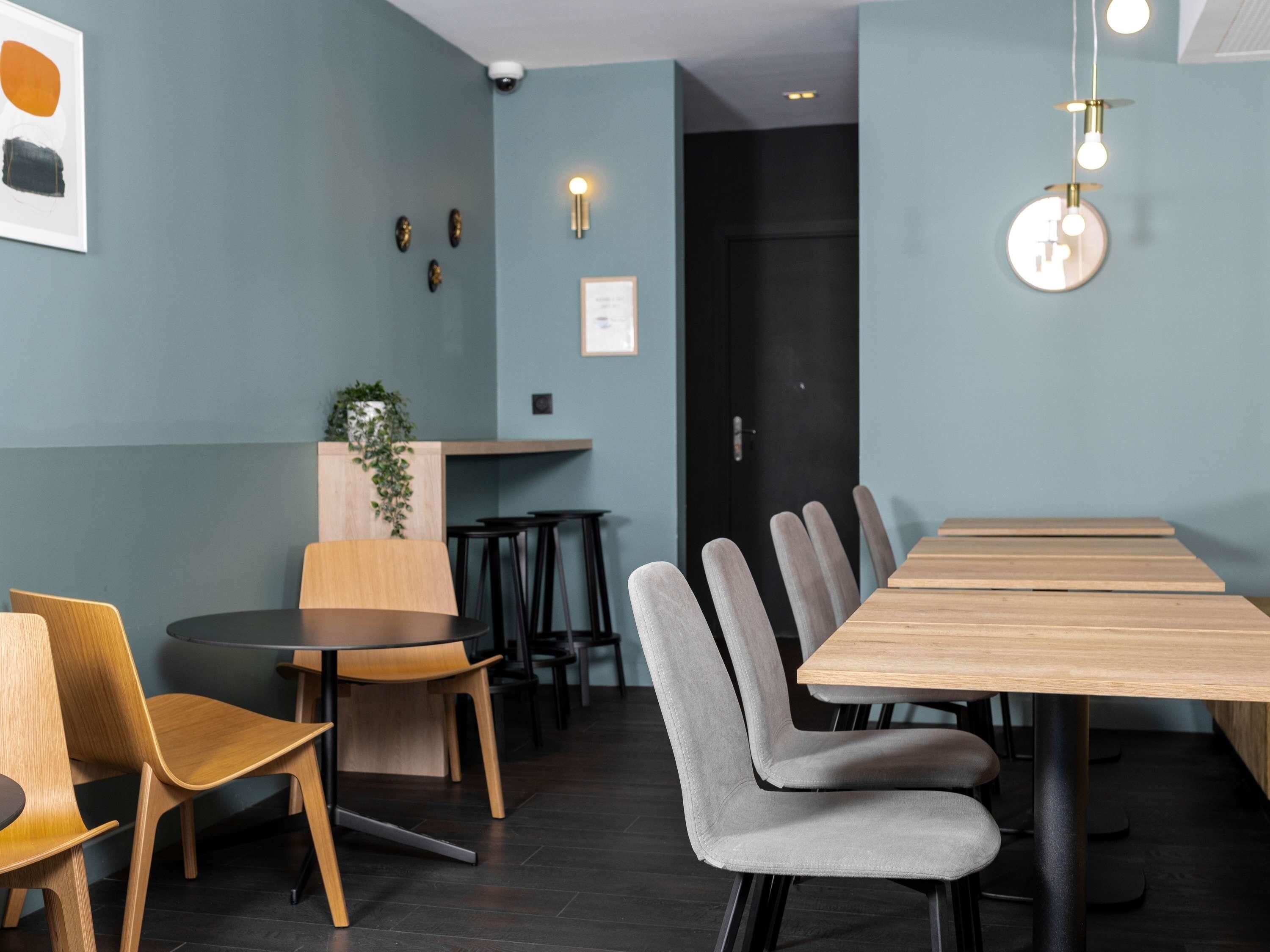 Un comedor moderno con una larga mesa de madera, sillas tapizadas de gris y una mesa redonda con sillas de madera.