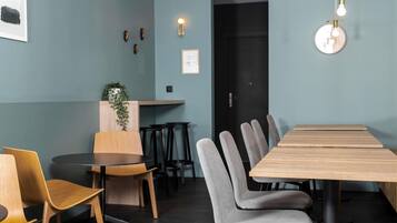 Un comedor moderno con una larga mesa de madera, sillas tapizadas de gris y una mesa redonda con sillas de madera.