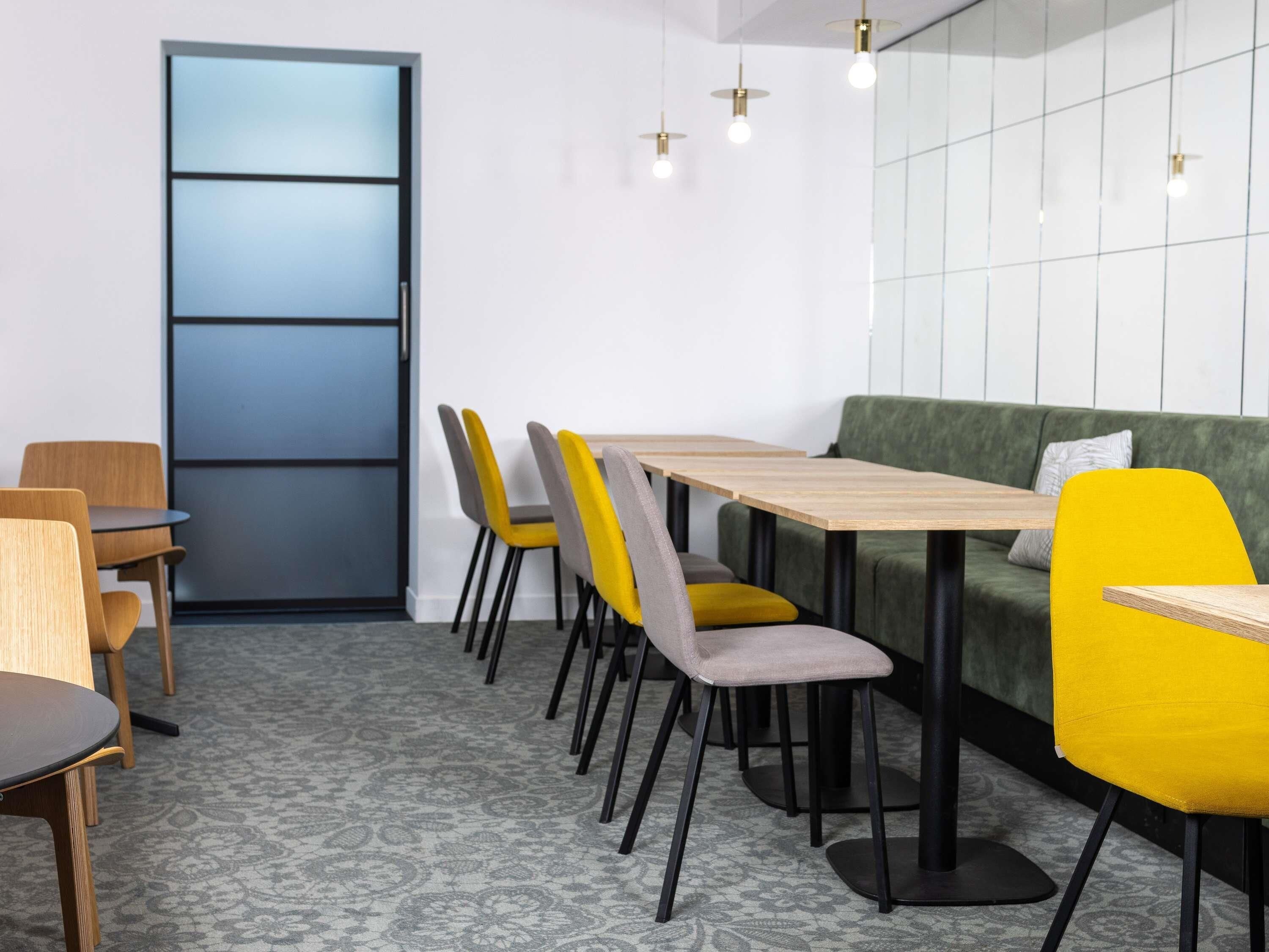 Un comedor moderno con una mesa larga, múltiples sillas y un sofá verde.