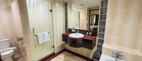 A modern bathroom with a toilet, sink, mirror, and bathtub.