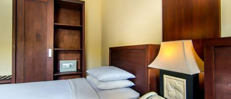 A hotel room with a bed, a bedside table with a lamp, a phone, and a safe.