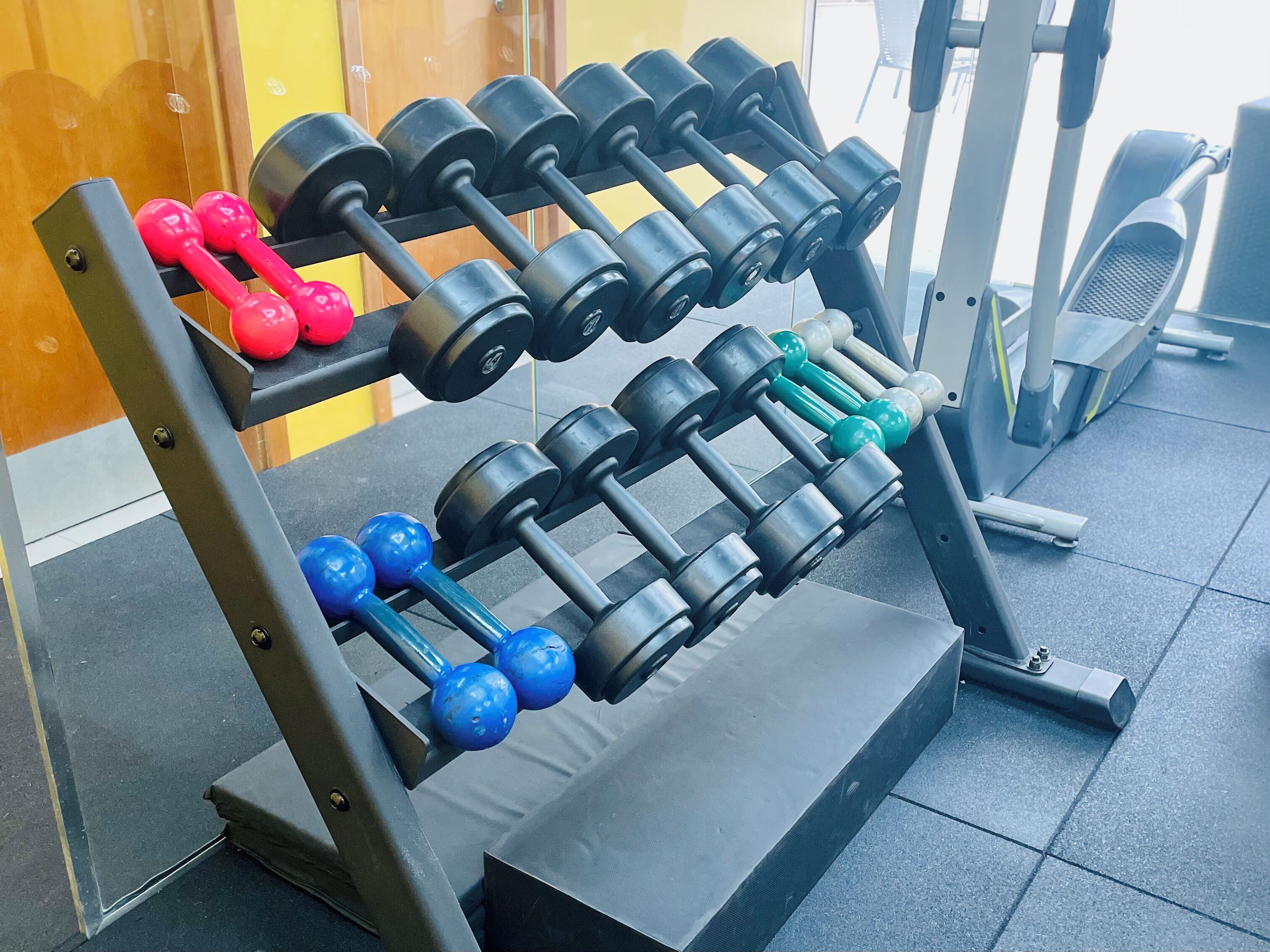 Ein Fitnessraum mit einer Hantelbank in verschiedenen Farben.