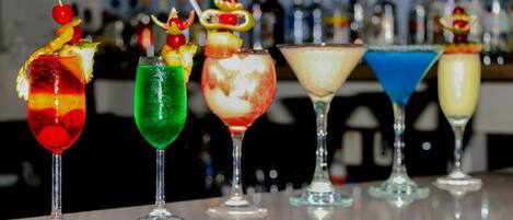 A bar with a variety of colorful cocktails, each garnished with fruits and other decorations.