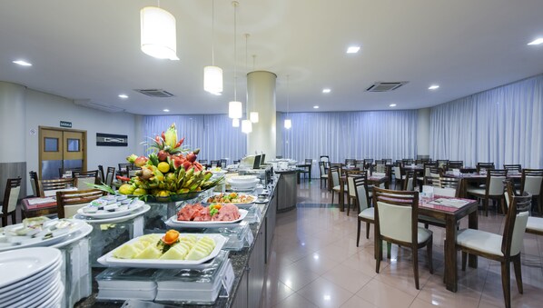 Een buffetopstelling met diverse gerechten en een groot fruitarrangement.