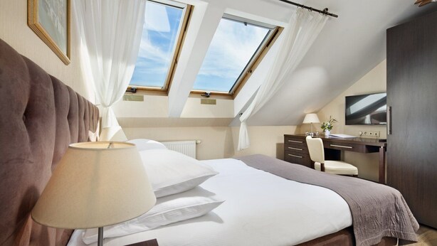 A bedroom with a large bed, a desk, and two skylights. - Hotel Bonum (Gdansk)