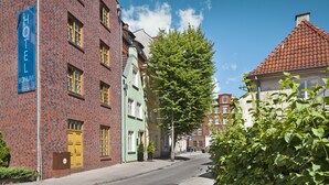 A hotel with a prominent sign, a brick facade, and a tree-lined street. - Hotel Bonum (Gdansk)
