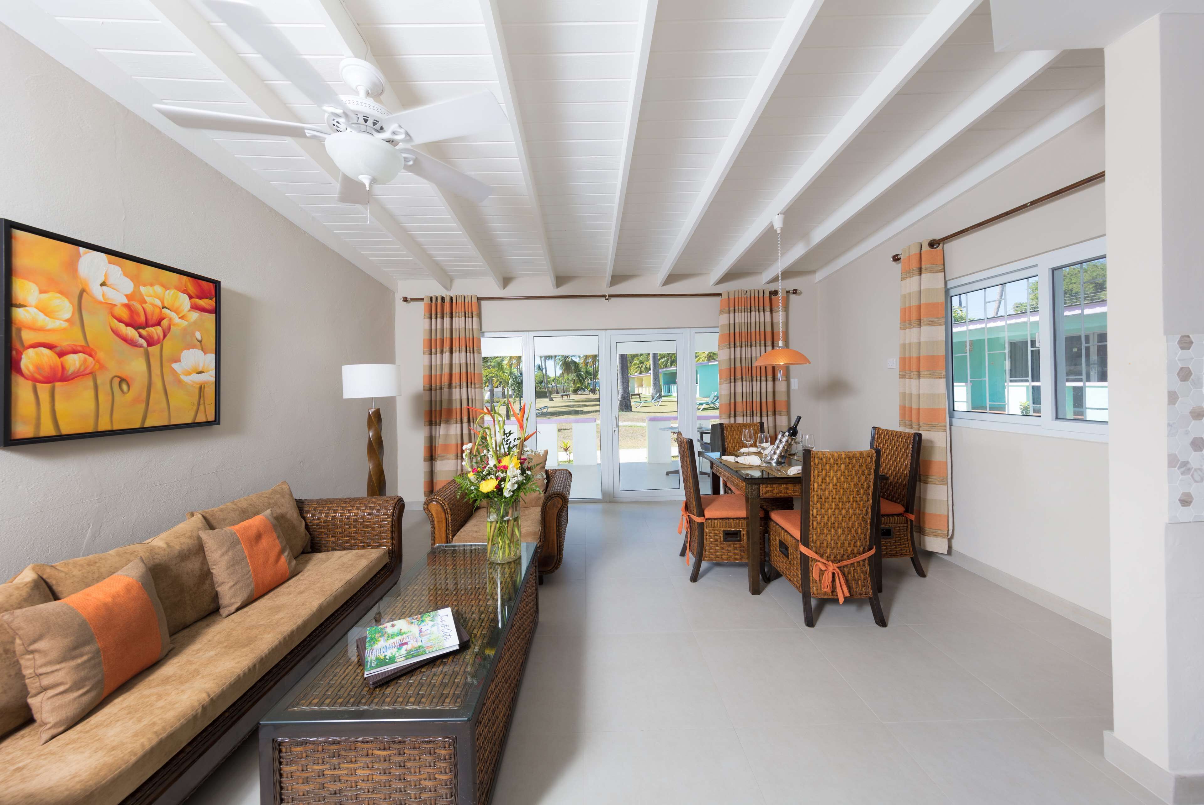 A modern living room with a sofa, dining table, chairs, and a ceiling fan.