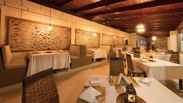 A restaurant with tables set for dining, featuring a brick wall with decorative panels and a wooden ceiling.